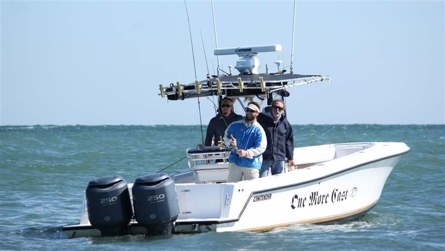 Capt. John McMurray (left) and Lee Crockett (right) watch as Aaron Podey, a former Pew fish policy expert, brings in a big striped bass.