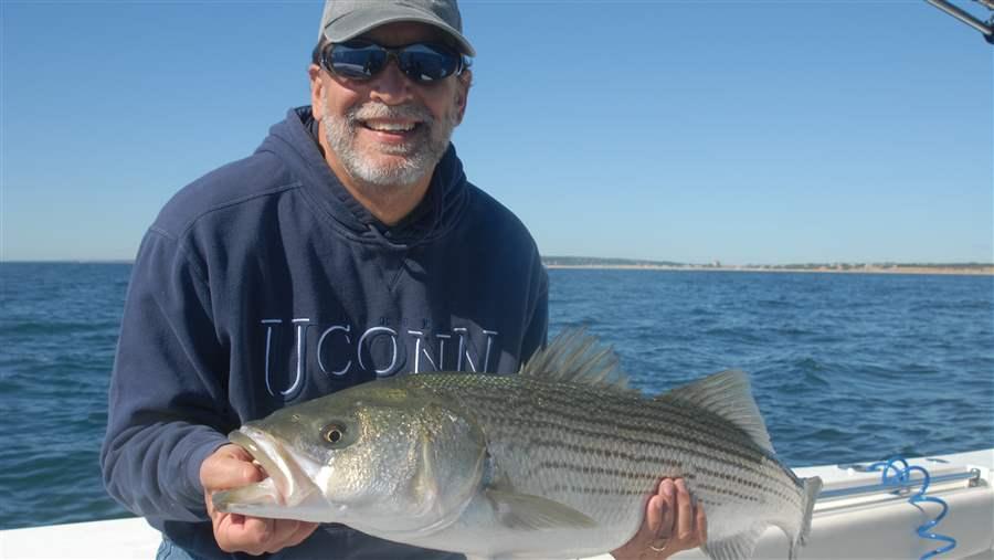 Lee Crockett poses with his catch—a 15-pound striped bass—before releasing it to swim another day.