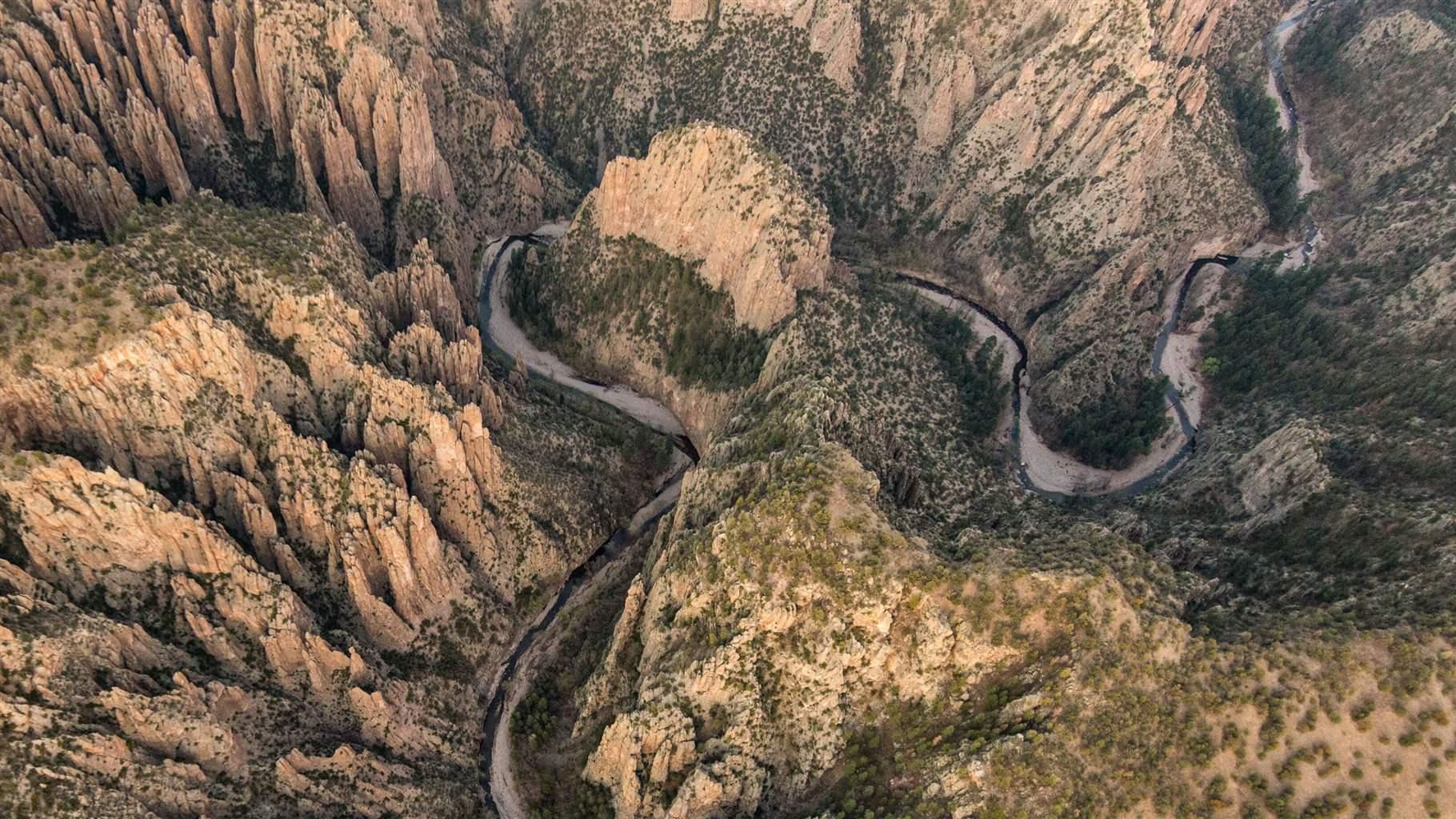 A areal shot of winding river with larger rock formations on every side