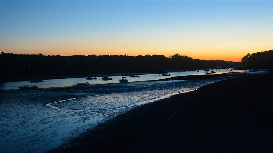 Sunsetting over a low riverbed with fishing boats all along. 