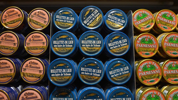 Three different canned tuna brands are pictured close-up on a market shelf.