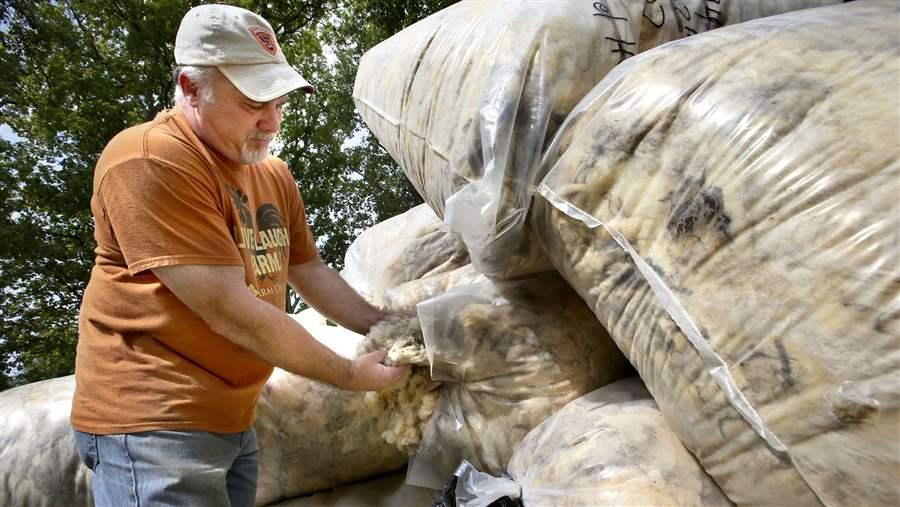 man checks bags of wool