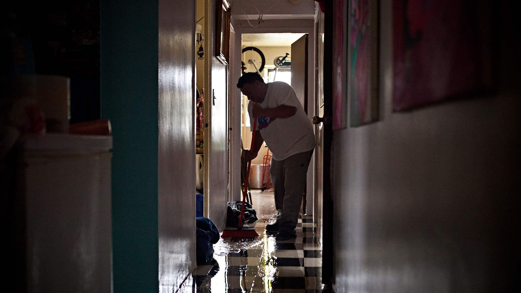 Bernadino Cruz sweeps water out of his apartment while cleaning up after flooding caused by Hurricane Sandy on October 30, 2012, in the Lower East Side of New York, United States