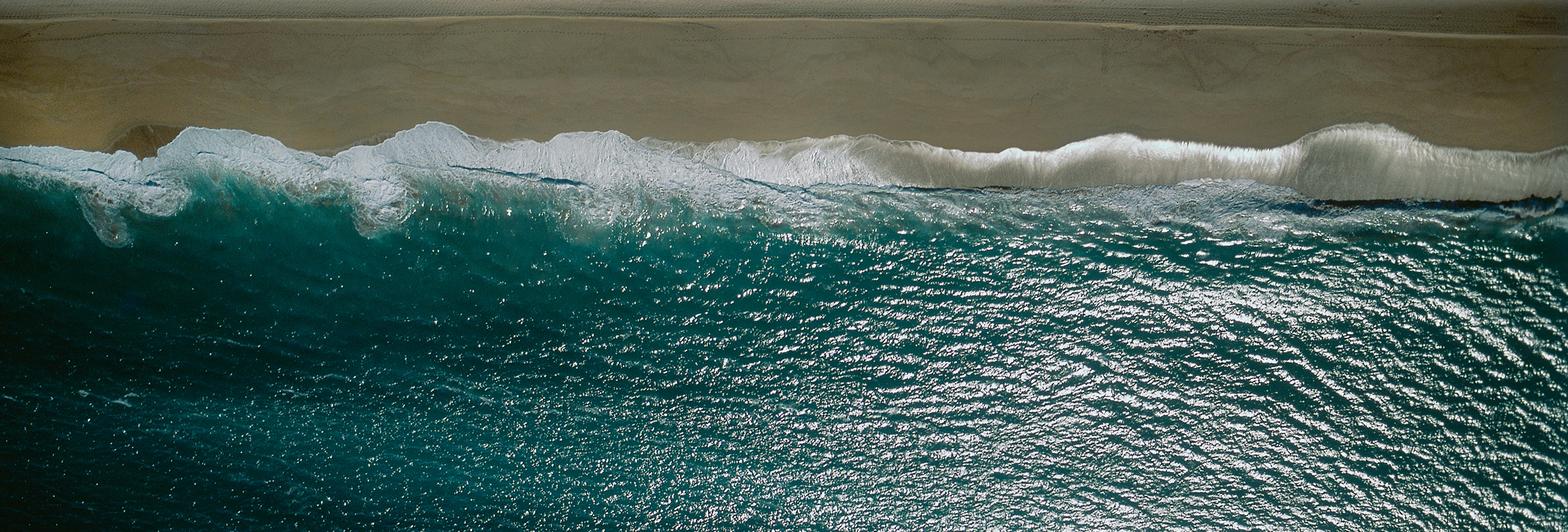 aerial view of a wave crashing on beach