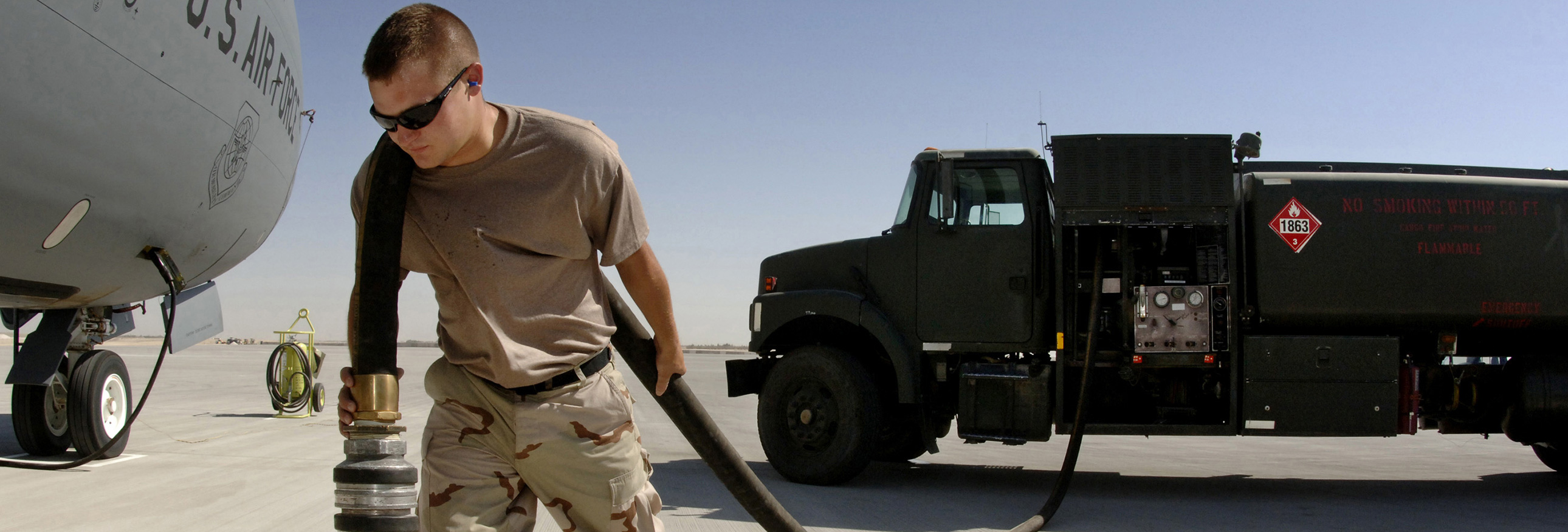 soldier pulling a hose from a gasoline truck on tarmac