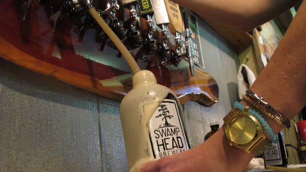 A man pours beer from a tap into a growler.