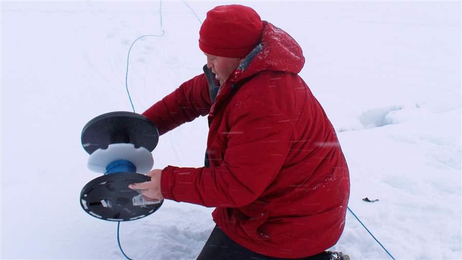  Alex Ootoowak unwinds more than 150 metres of rope before deploying the first hydrophone through the ice in Milne Inlet.