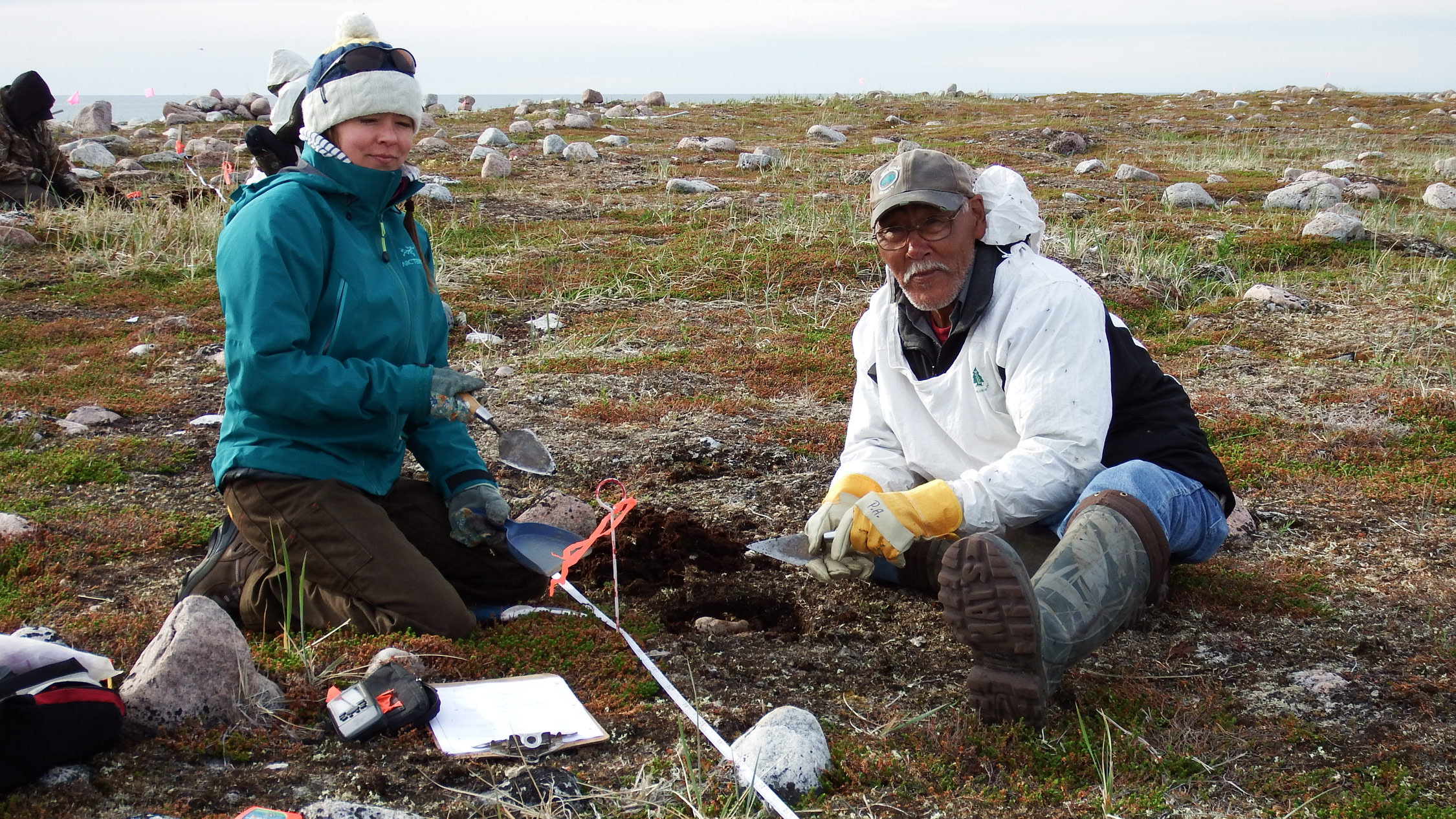 Kristin Westdal, a marine biologist with Oceans North Canada, conducts a shovel test with Peter Alareak of Arviat, Nunavut.