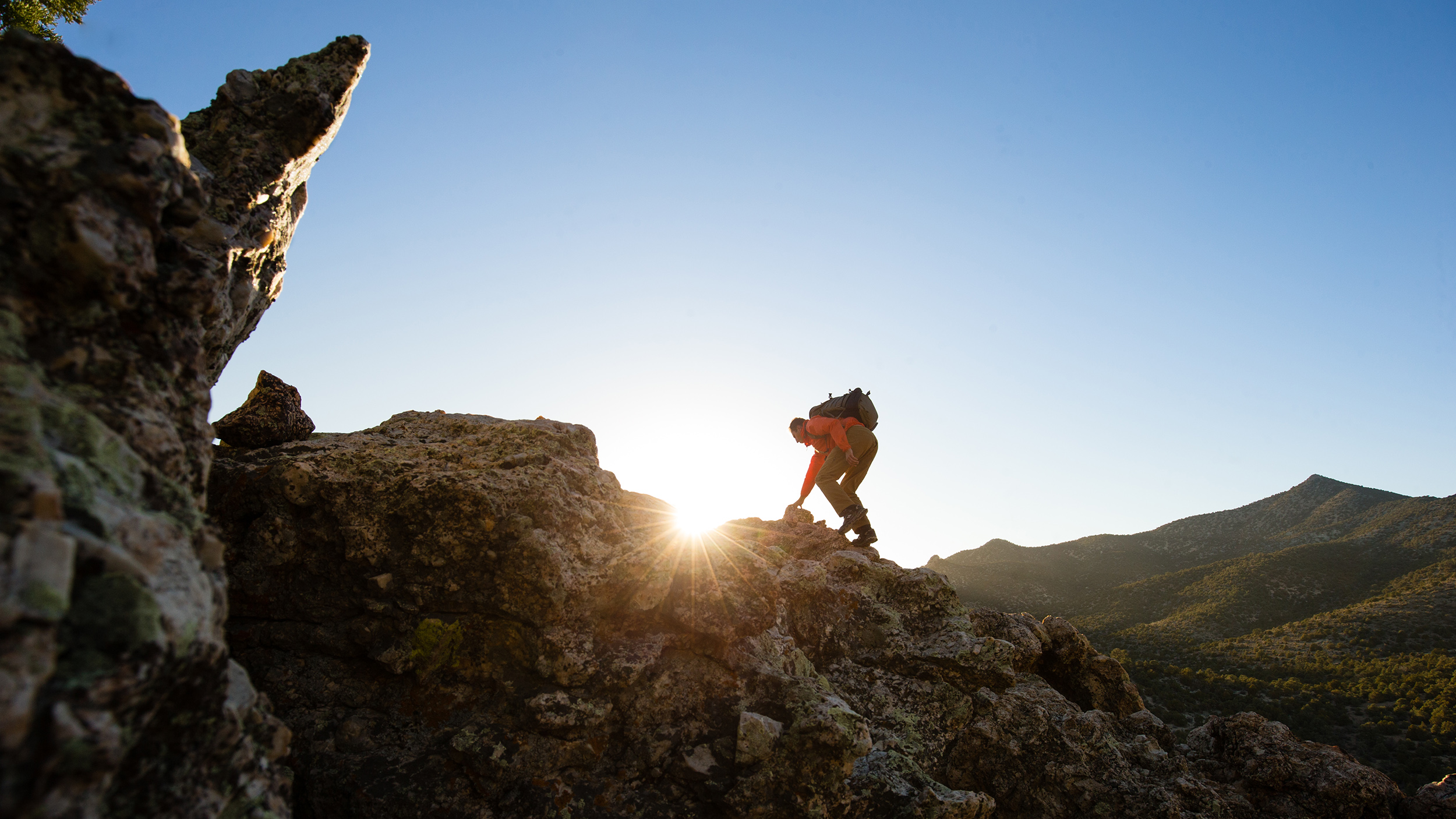 A hiker scrambles across rocks in the Mount Irish Range. 