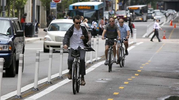 A bicyclist looks at an electronic device A bicyclist looks at an electronic device