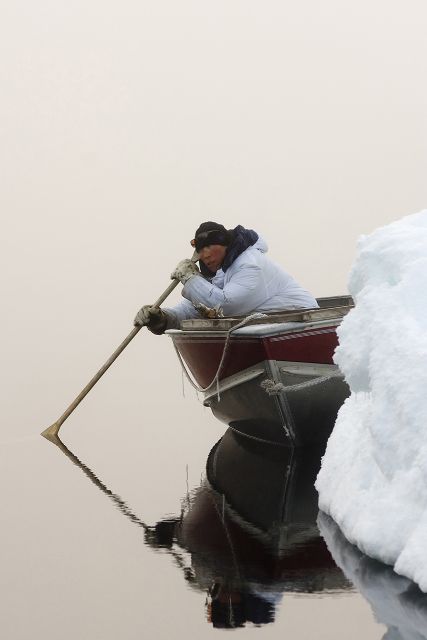 An Inupiat hunter uses a wooden oar to listen for passing bowheads during the spring whaling season in the Chukchi Sea.
