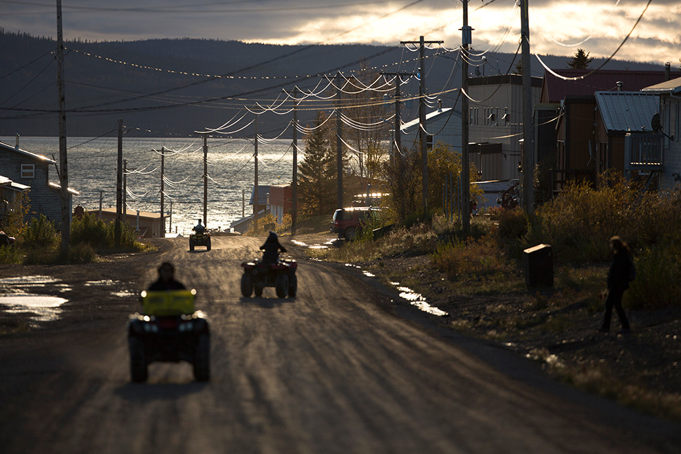 All terrain vehicles driving down a street by the water