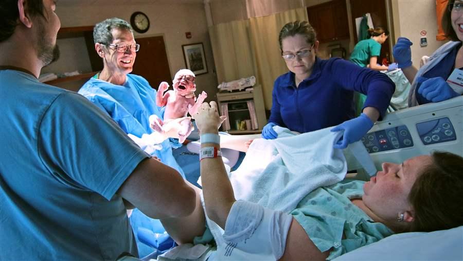 An obstetrician holds a newborn boy 