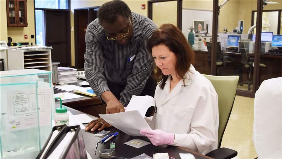 Forensic scientist Pamela Kitchens and lab director Sherwin Boswell examine heroin at a lab