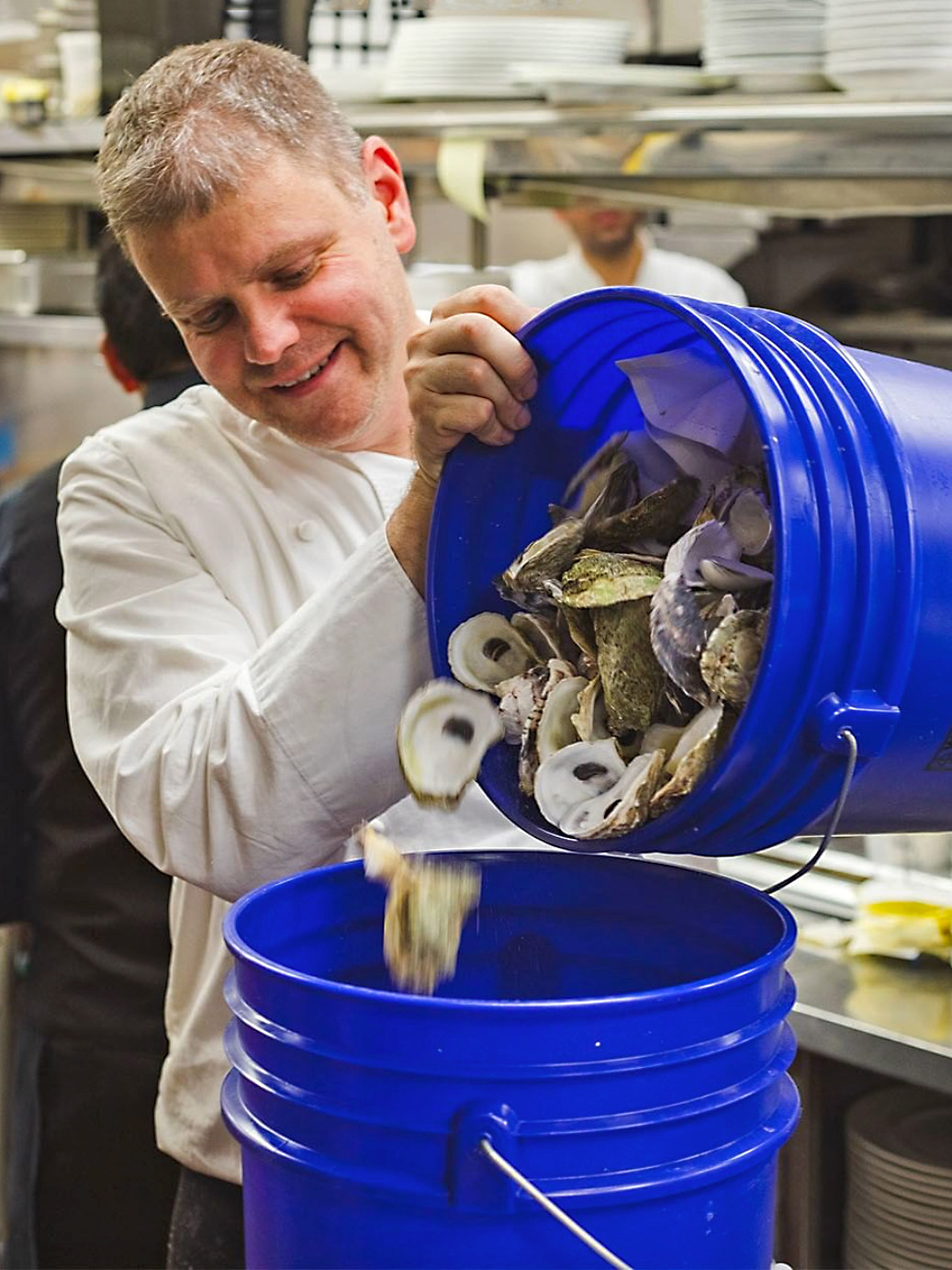 A New York chef pours oyster shells from one bucket into another. The shells will be collected and recycled by the Billion Oyster Project.