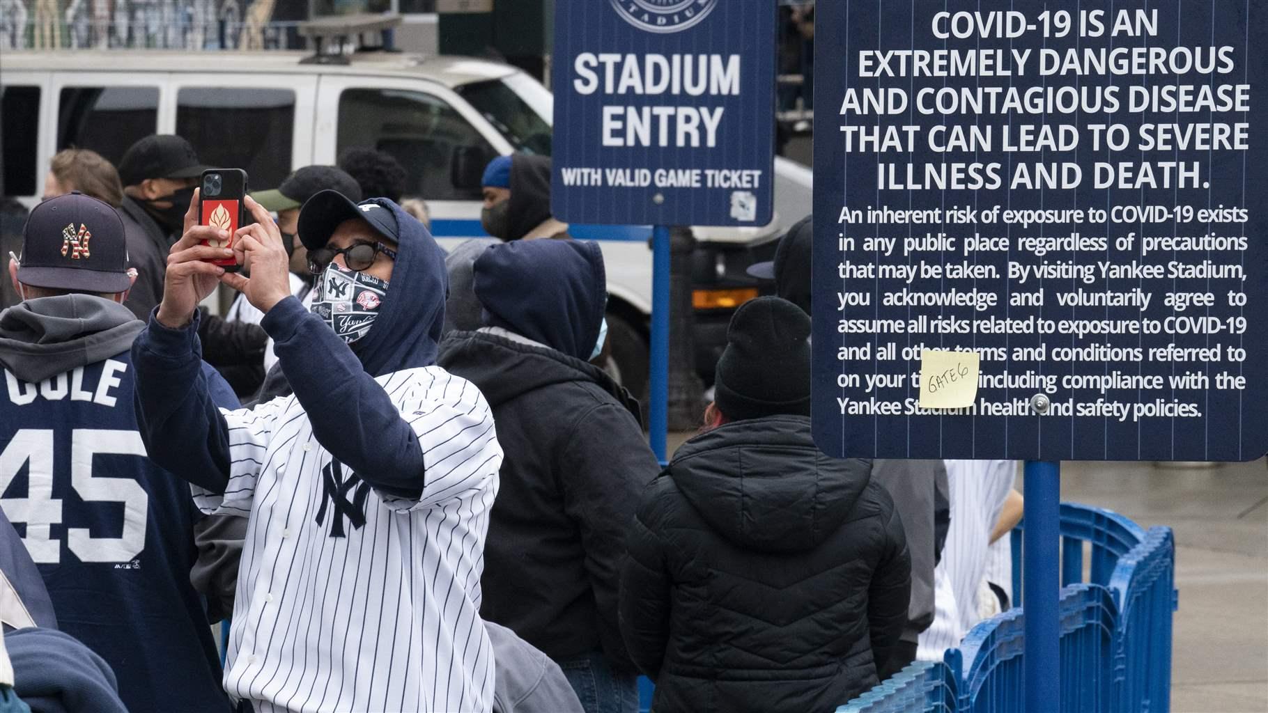Yankee fan taking picture with COVID warning sign
