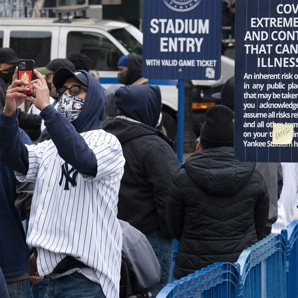 Yankee fan taking picture with COVID warning sign