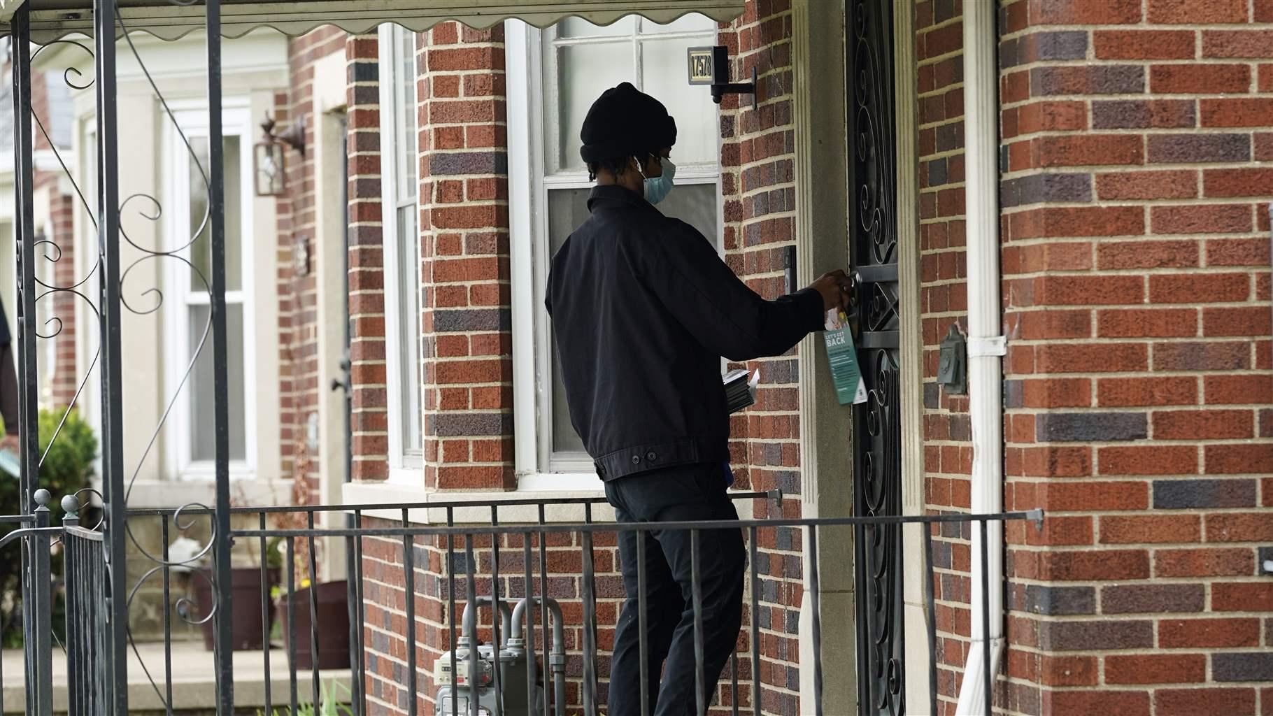 Deares Carey leaves a flyer on a home in Detroit, Tuesday, May 4, 2021. Officials are walking door-to-door to encourage residents of the majority Black city to get vaccinated against COVID-19 as the city's immunization rate lags well behind the rest of Michigan and the United States.