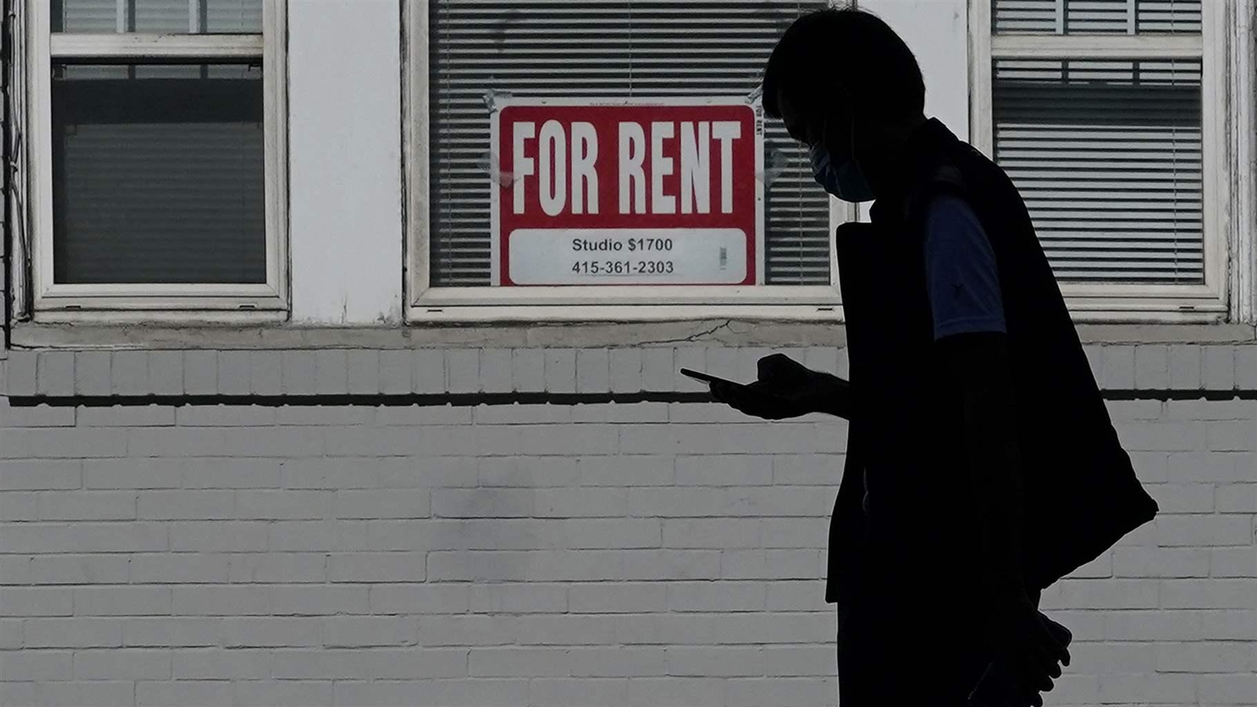 man walks past a For Rent sign 