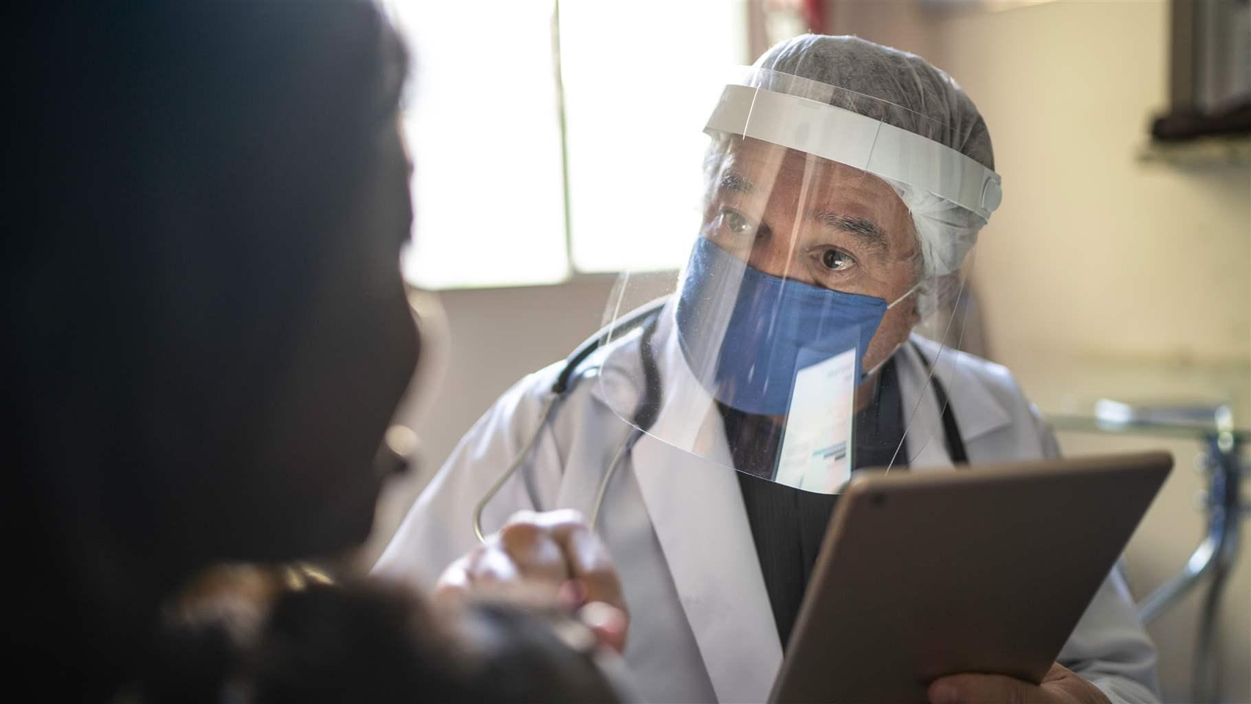 Doctor wearing protective face mask on medical consultation at home