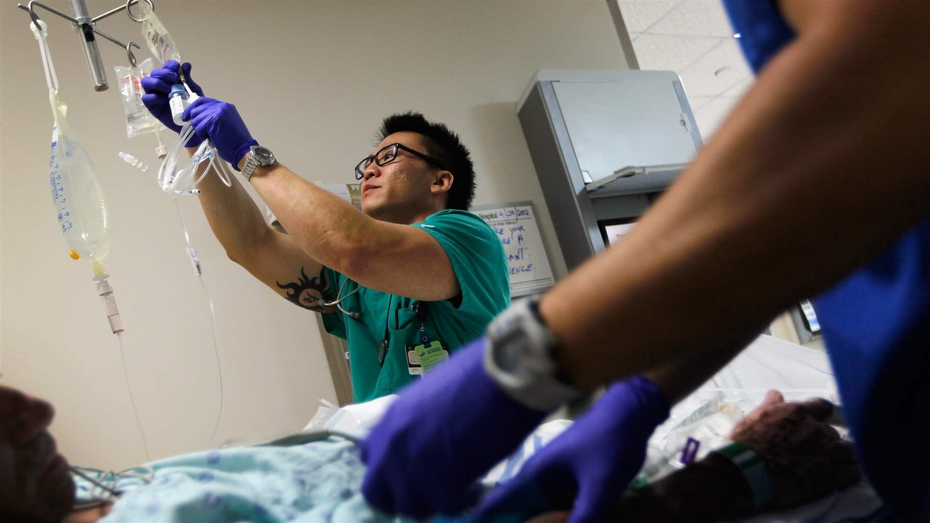 Registered Nurse Tung Tran hangs an I.V. bag for a patient at the University of Miami Hospital's Emergency Department on April 30, 2012 in Miami, Florida.