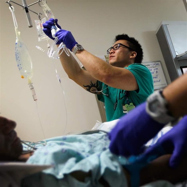 Registered Nurse Tung Tran hangs an I.V. bag for a patient at the University of Miami Hospital's Emergency Department on April 30, 2012 in Miami, Florida.