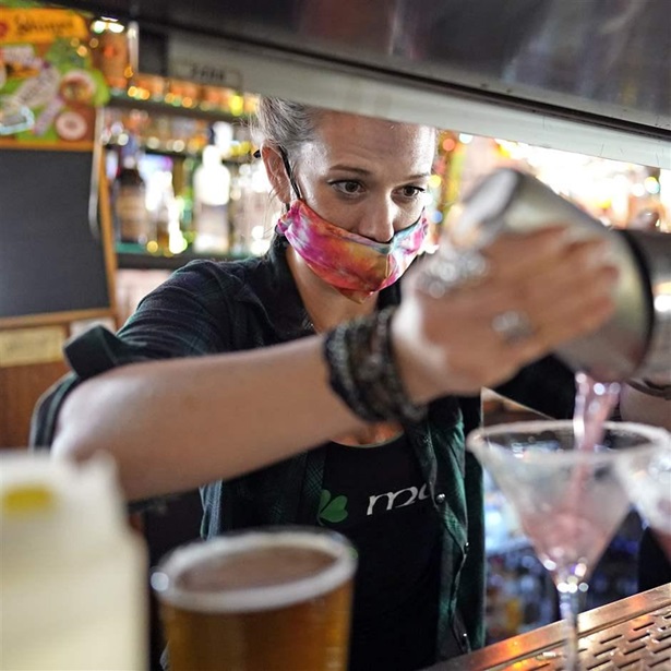 Bartender Alyssa Dooley makes a cocktail at Mo's Irish Pub, Tuesday, March 2, 2021, in Houston. Texas Gov. Greg Abbott announced Tuesday that he is lifting business capacity limits and the state's mask mandate starting next week.
