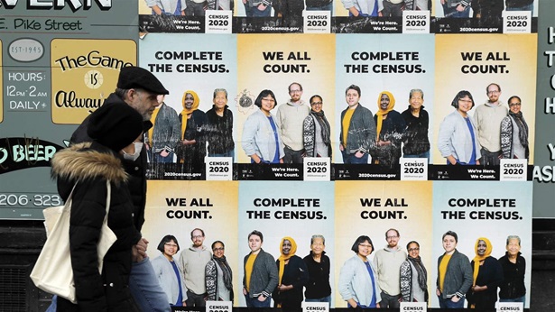 In this April 1, 2020, file photo, people walk past posters encouraging participation in the 2020 Census in Seattle's Capitol Hill neighborhood