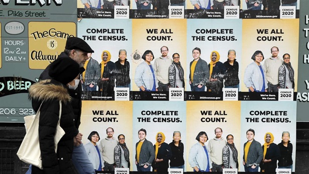 VIRUS OUTBREAK-CENSUS SURVEY In this April 1, 2020, file photo, people walk past posters encouraging participation in the 2020 Census in Seattle's Capitol Hill neighborhood