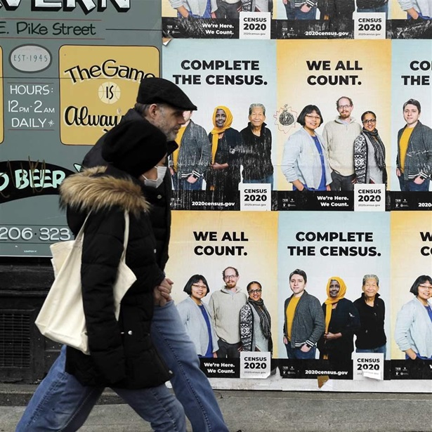 VIRUS OUTBREAK-CENSUS SURVEY In this April 1, 2020, file photo, people walk past posters encouraging participation in the 2020 Census in Seattle's Capitol Hill neighborhood