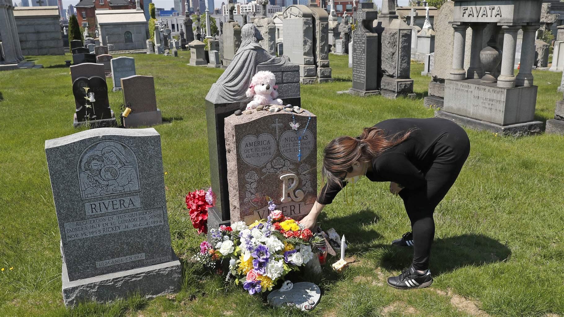 At a cemetery in New York, a woman adjusts flowers at the grave of her daughter who died of a drug overdose when she was 21. At a cemetery in New York, a woman adjusts flowers at the grave of her daughter who died of a drug overdose when she was 21.