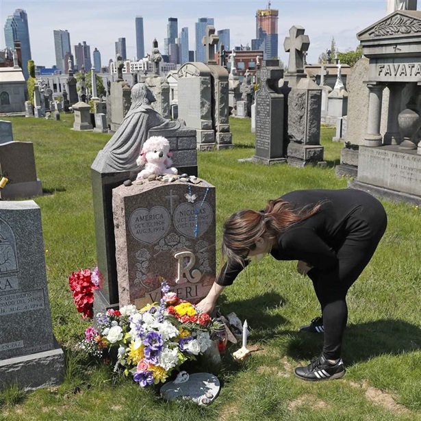 At a cemetery in New York, a woman adjusts flowers at the grave of her daughter who died of a drug overdose when she was 21.