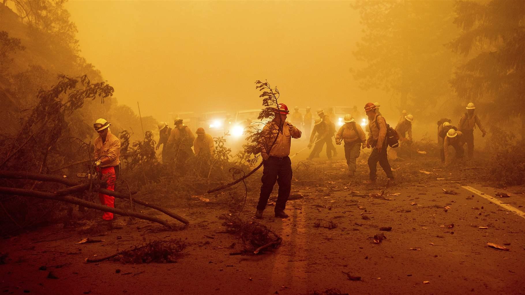 Firefighters battling the Dixie Fire clear Highway 89 in Plumas County, California