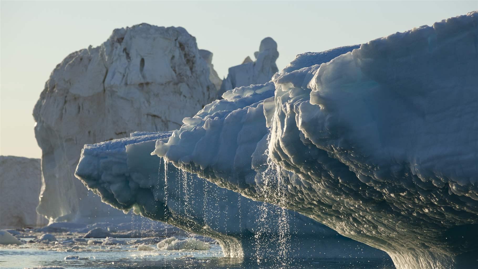 Massive icebergs from Jakobshavn Glacier melting in Disko Bay on sunny summer evening, Ilulissat, Greenland.