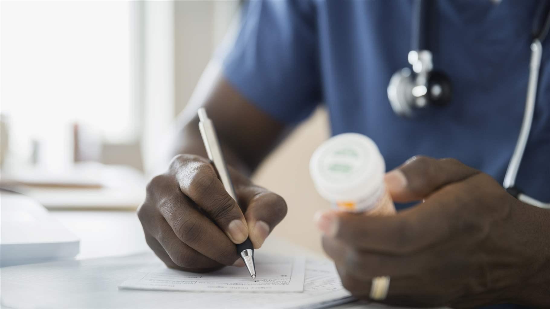 Close up of doctor with bottle writing prescription