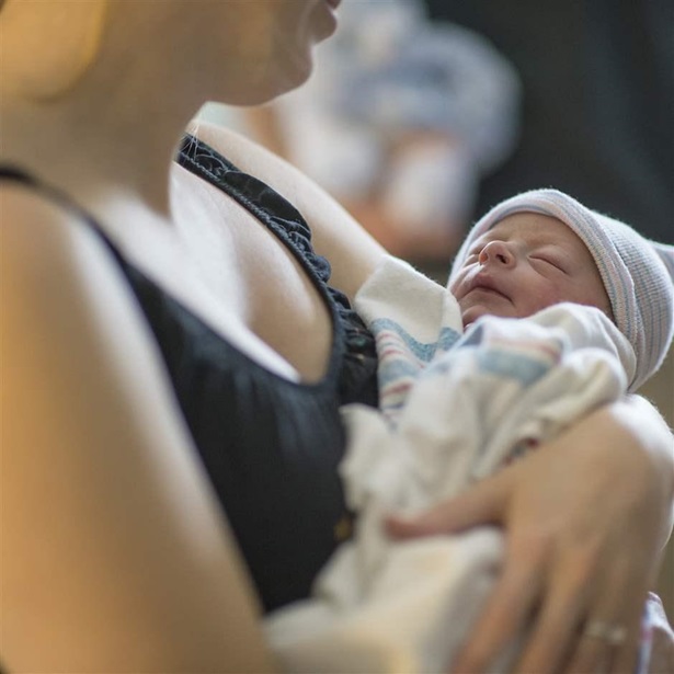 In this Wednesday, July 25, 2018 photo, Bethany Schroeder, left, holds her newborn son Brooks at IU Health hospital in Bloomington, Ind. Britt Miller, a 911 dispatcher, talked Bethany's mother-in-law Kim Schroeder into helping deliver Bethany's newborn son Brooks when she went into in labor at home.