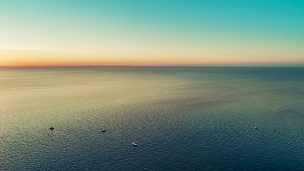 Small boats in vast sea at dusk