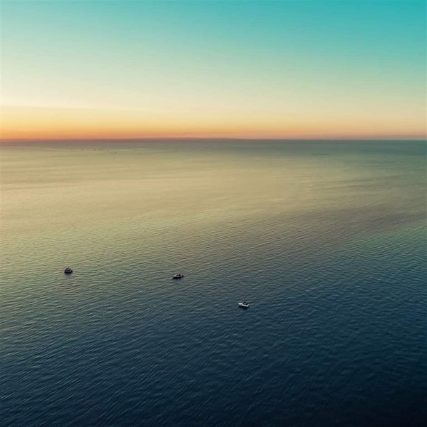 Small boats in vast sea at dusk