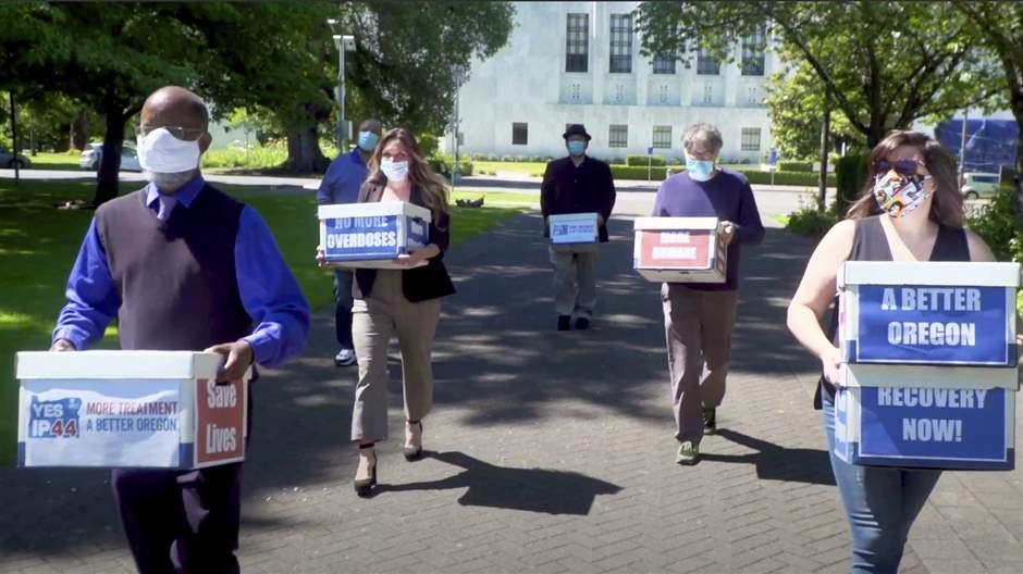 This June 26, 2020 file photo from video provided by the Yes on Measure 110 Campaign shows volunteers delivering boxes containing signed petitions in favor of the measure to the Oregon Secretary of State's office in Salem.