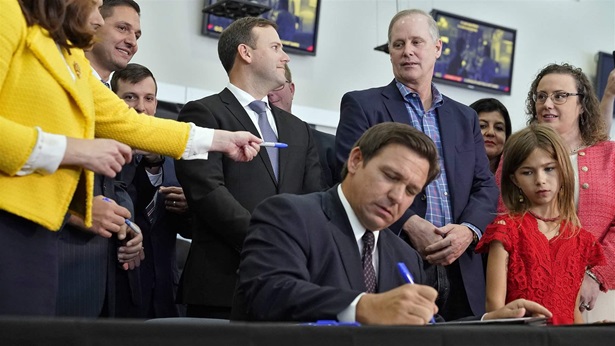 Florida Gov. Ron DeSantis, a Republican, signs a bill during a news conference in Brandon, Fla. At least 14 states have debated bills to fight the Biden administration’s vaccination requirements.