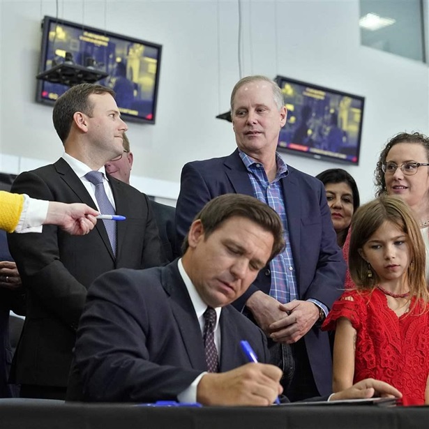 Florida Gov. Ron DeSantis, a Republican, signs a bill during a news conference in Brandon, Fla. At least 14 states have debated bills to fight the Biden administration’s vaccination requirements.