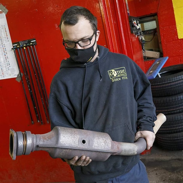 Ari Thielman, manager at GT Tire & Service Center in Meridien, Conn., holds a catalytic converter from a Ford F-150 that the business replaced for a customer. Catalytic converter theft has skyrocketed in the past few years, and legislatures are trying to address the problem