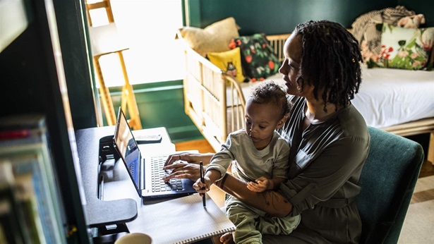 Woman working from home while holding toddler