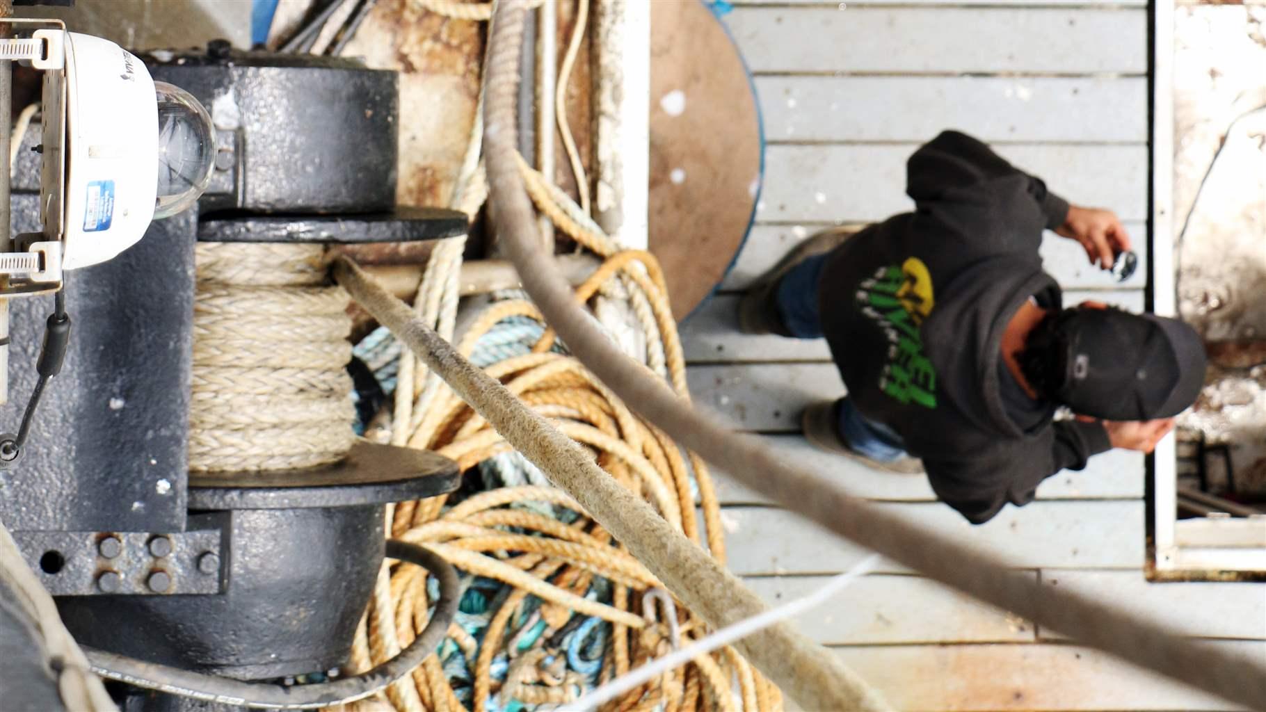 Birds eye view of a fisherman working lines and netting. 