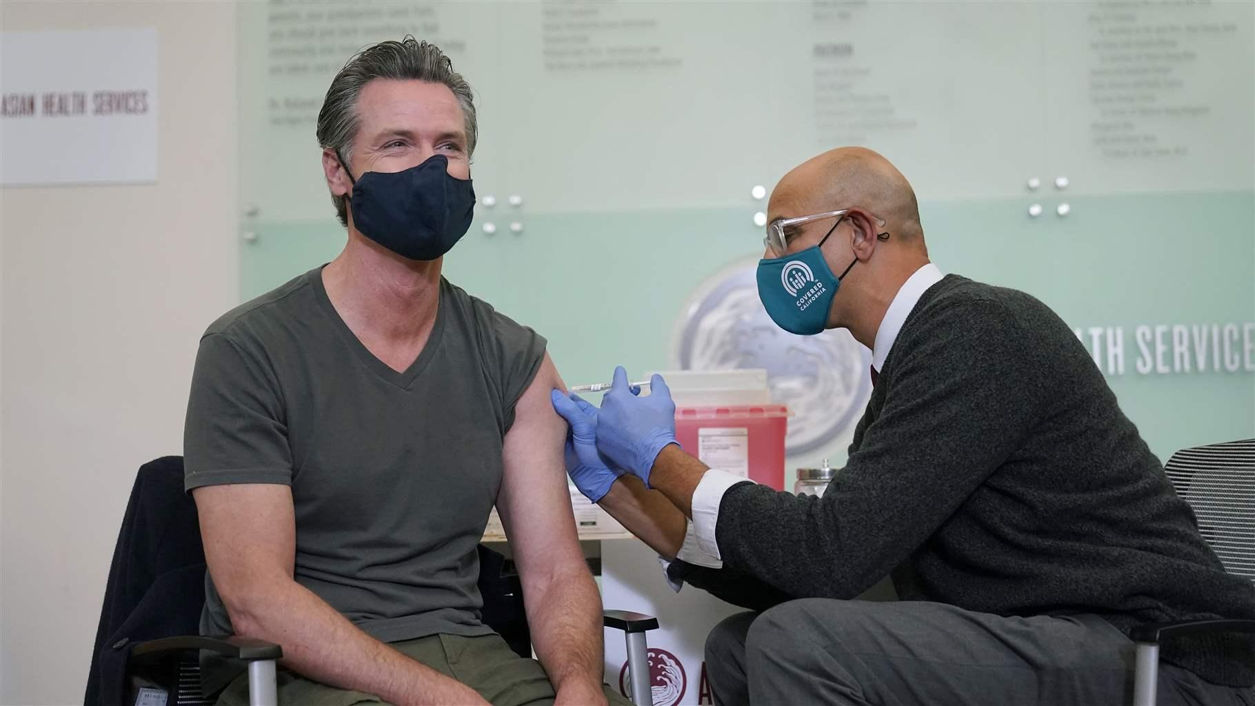 California Gov. Gavin Newsom, left, receives a Moderna COVID-19 vaccine booster shot from California Health and Human Services Secretary Dr. Mark Ghaly at Asian Health Services in Oakland, Calif., Wednesday, Oct. 27, 2021.