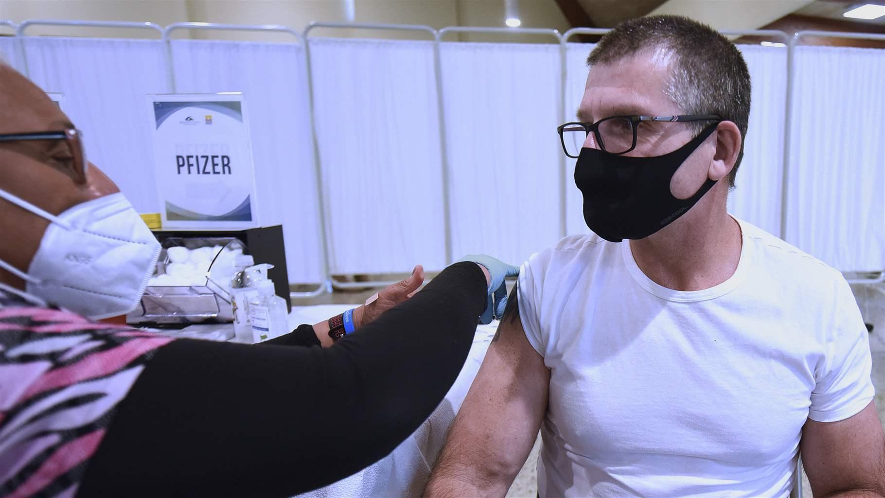 A health worker administers a dose of Pfizer COVID-19 vaccine to a man at Sanford Civic Center.