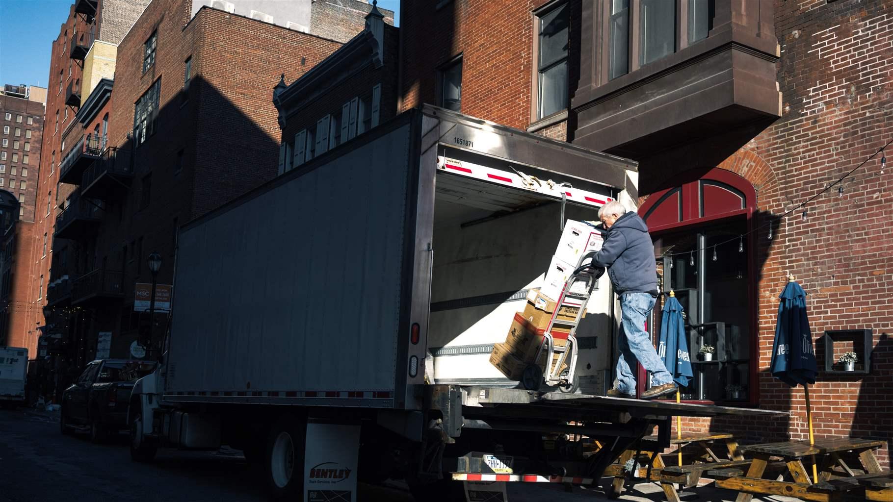 A man is unloading supplies at a loading dock of a building.