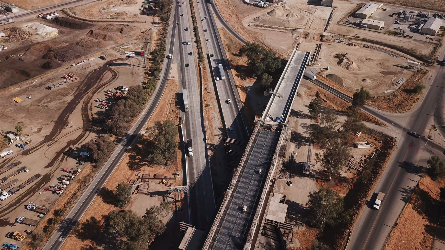 An aerial photo of a viaduct during construction with a highway and traffic below. 