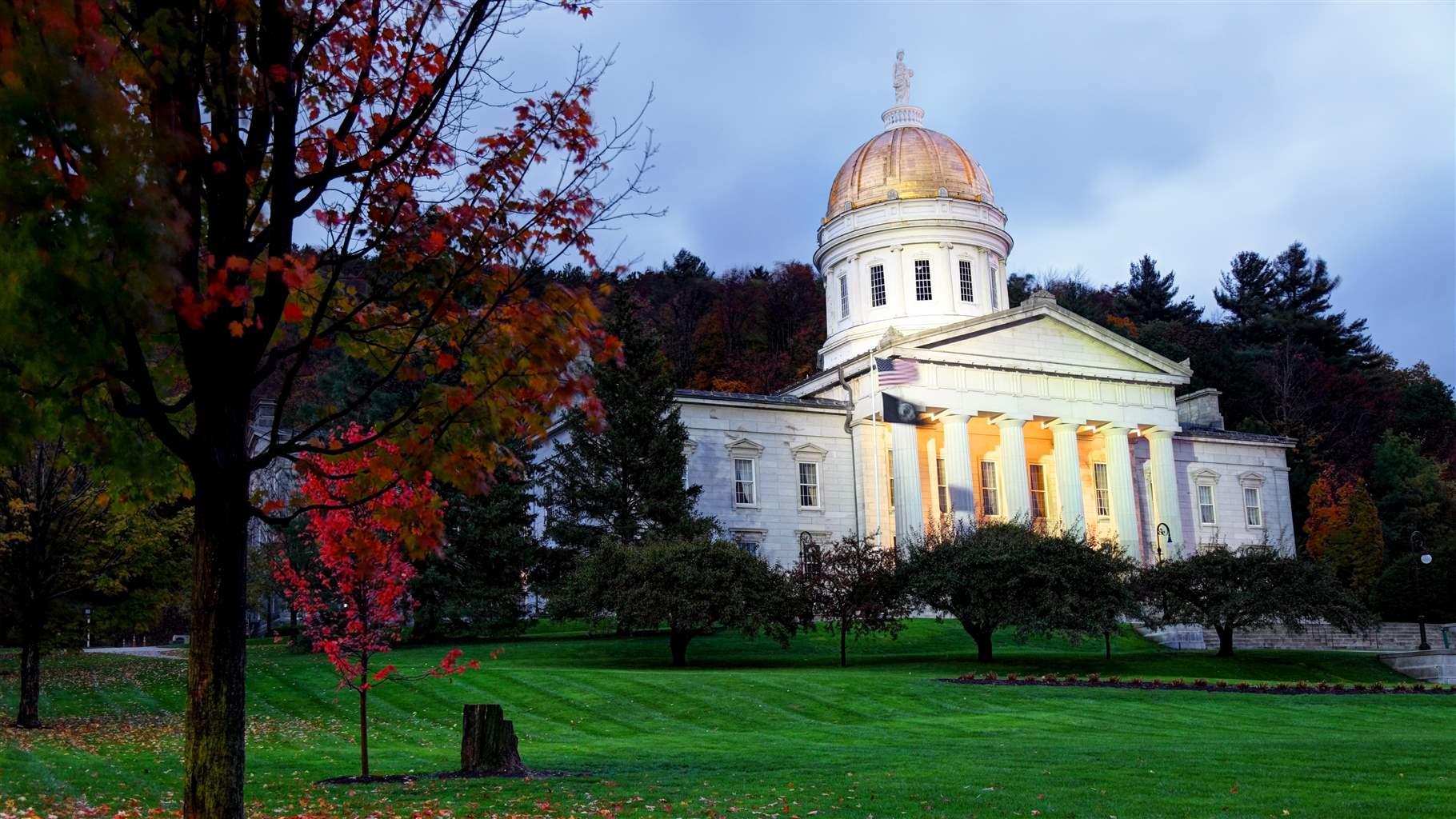 The Vermont state house in the fall surrounded by the changing leaves.  