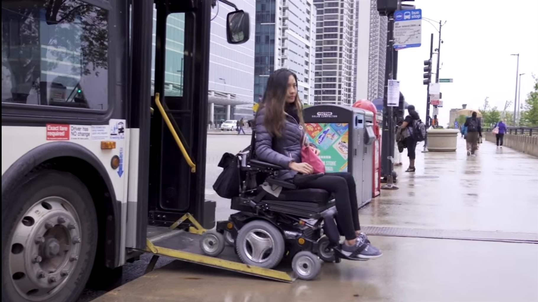 A woman in a wheelchair existing a city bus